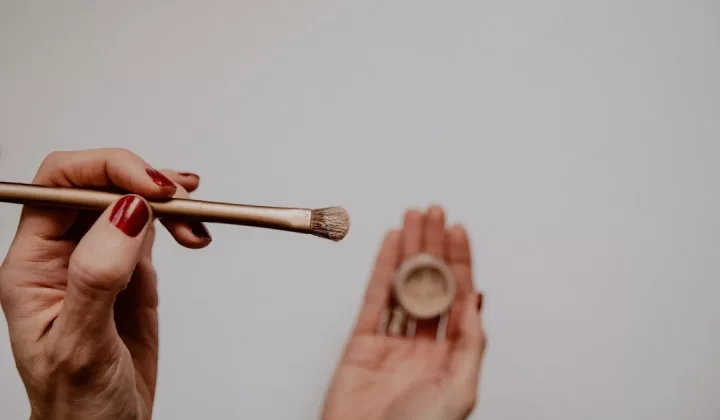 person holding brown and white makeup brush