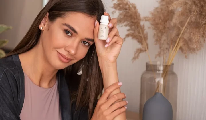 a woman holding a bottle of lotion next to her face