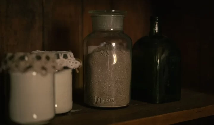Old jars and bottles on a dark wooden shelf.