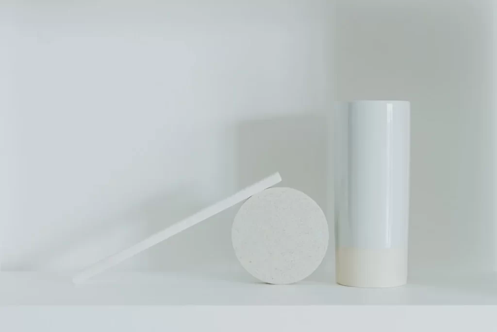a white vase sitting next to a white round object