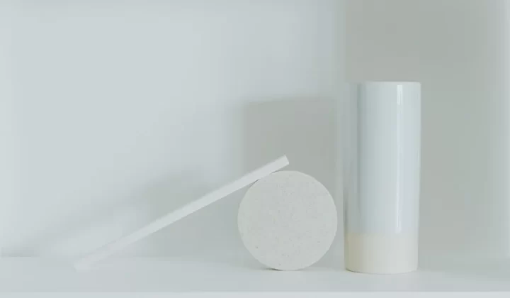 a white vase sitting next to a white round object