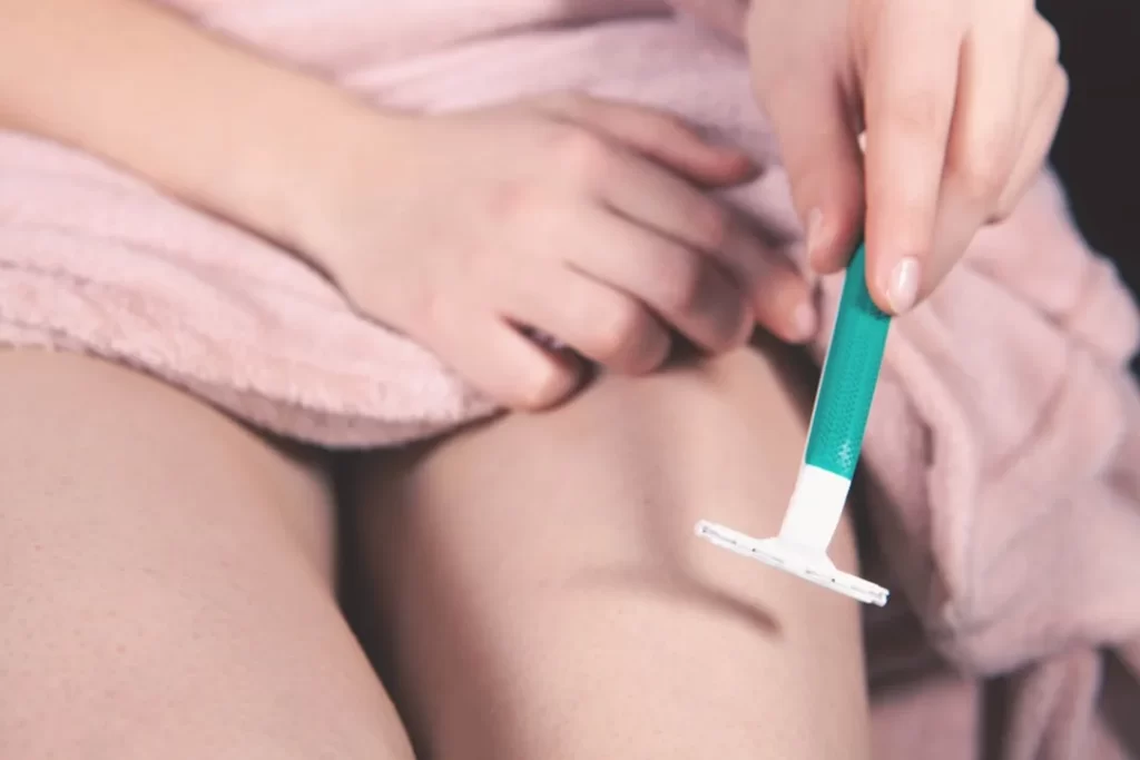 Person shaving leg with razor