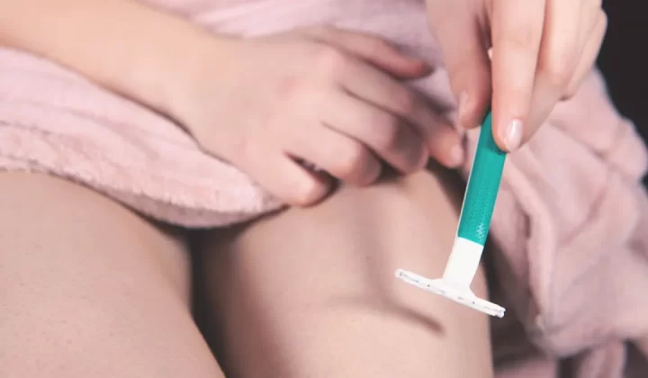 Person shaving leg with razor