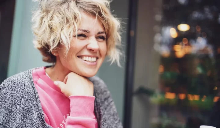 smiling girl in pink shirt and gray cardigan