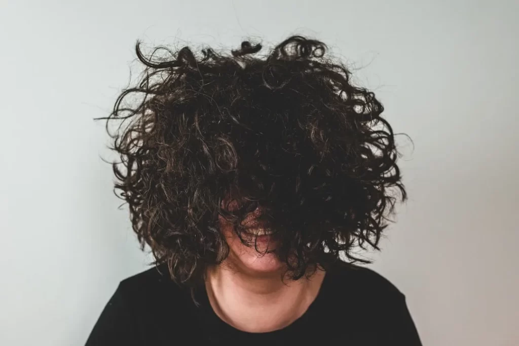 person with curly hair covering face