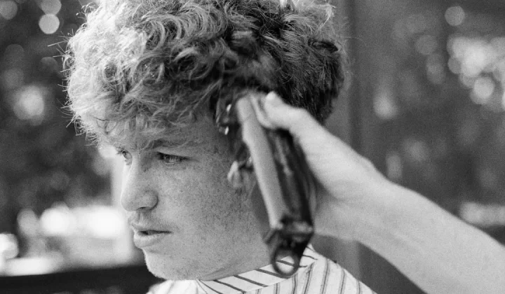 man in white and black stripe shirt holding hair clipper