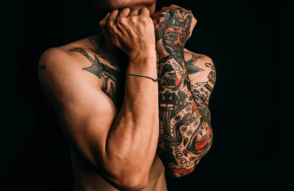 Man with fully tattooed arms against black background