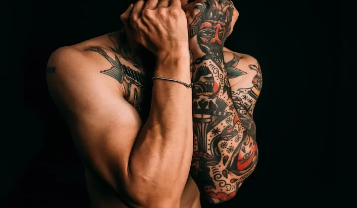 Man with fully tattooed arms against black background