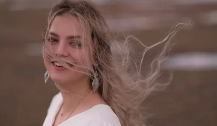 a woman with long hair is smiling and looking at the camera