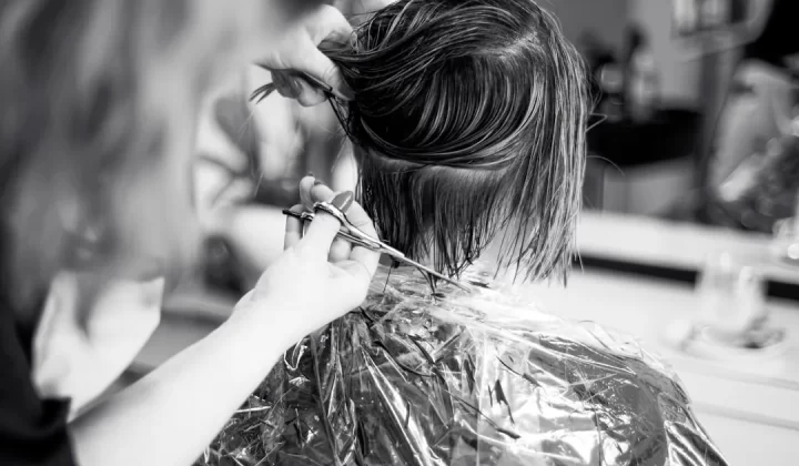 a woman cutting another woman's hair in a salon