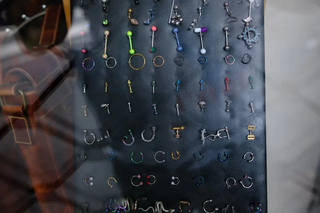 Many colorful body piercings and earrings on a dark display.