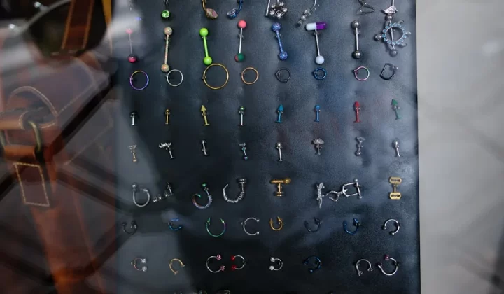 Many colorful body piercings and earrings on a dark display.