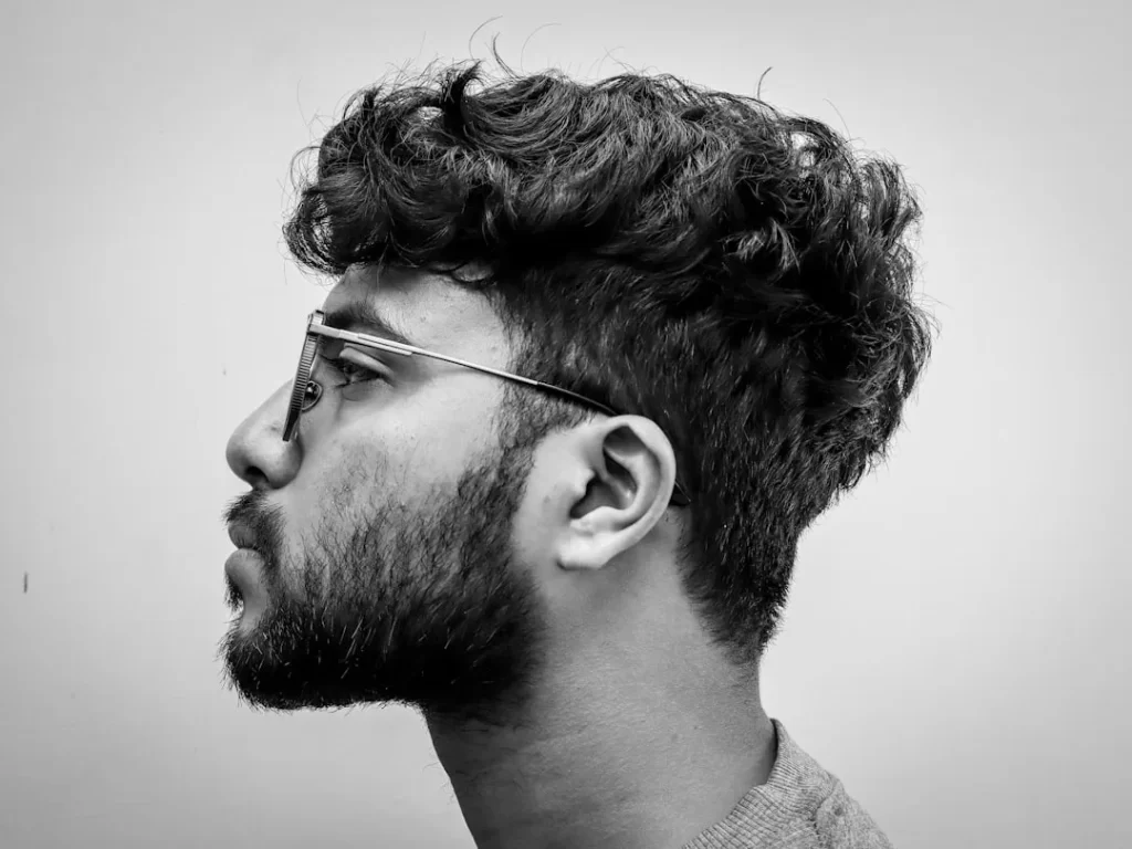 Man with glasses and curly hair in profile.