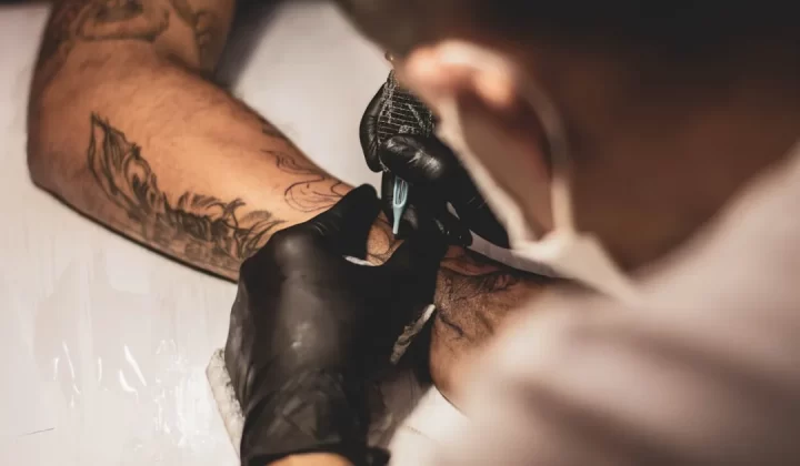 shallow focus photo of person tattooing person's right arm
