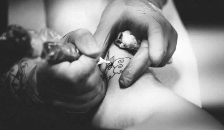 person doing flower tattoo on leg