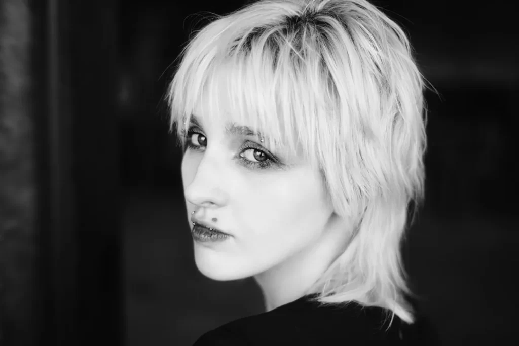 A woman with short, light hair looking over her shoulder.