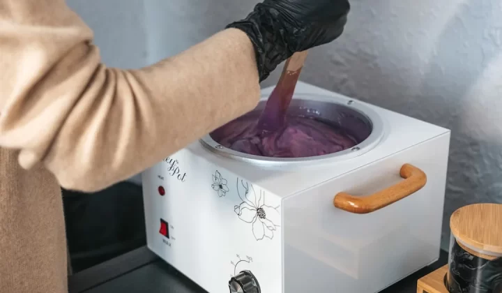 a person in black gloves stirring a pot of purple liquid