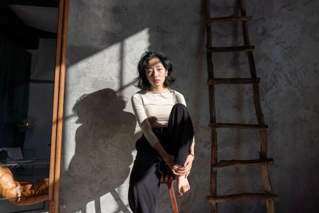 Woman sitting in a room with dramatic light and shadows.