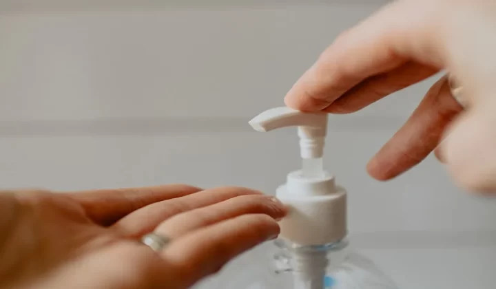person holding white plastic pump bottle