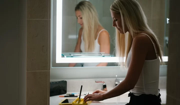 woman in white tank top standing in front of mirror