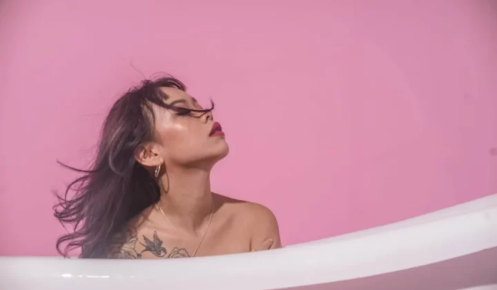a woman in a bathtub with her hair blowing in the wind