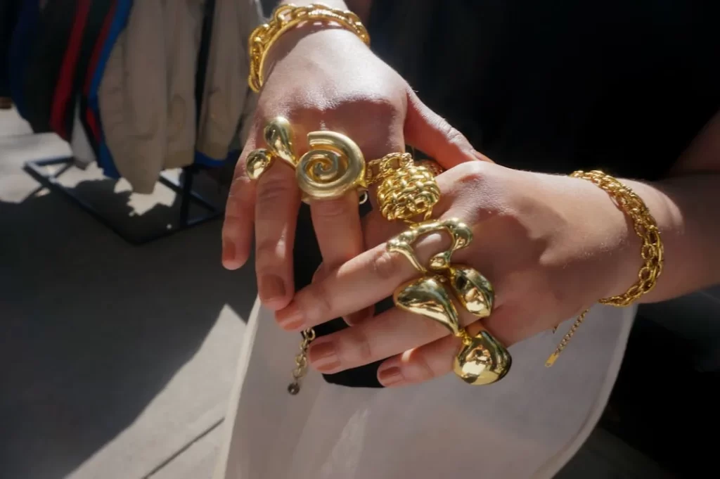 Hands adorned with chunky gold rings and bracelets.