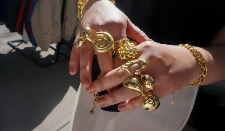Hands adorned with chunky gold rings and bracelets.