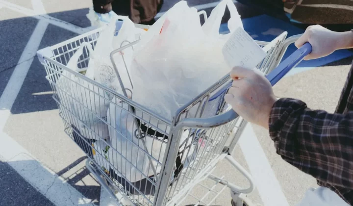 A person pushing a shopping cart full of bags