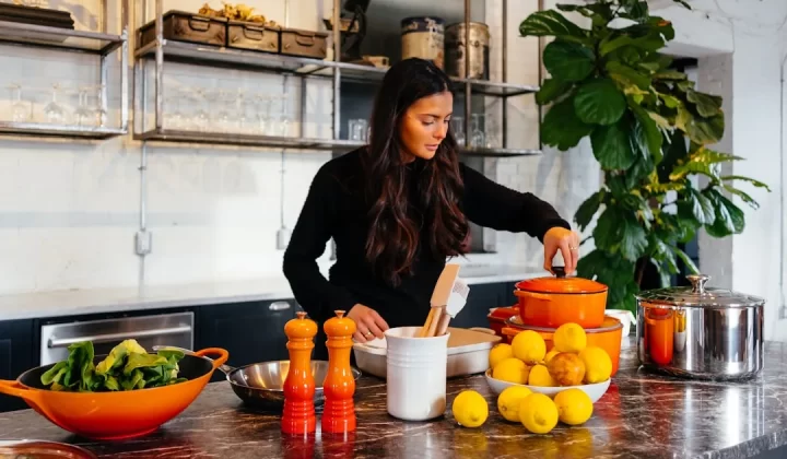 woman standing in front of fruits holding pot's lid