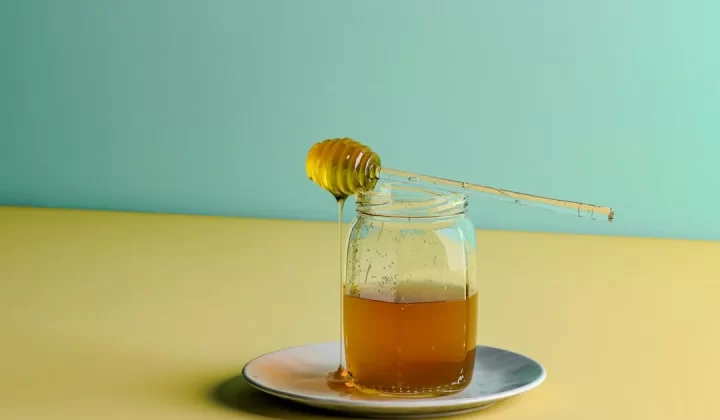 a glass jar filled with honey sitting on a plate