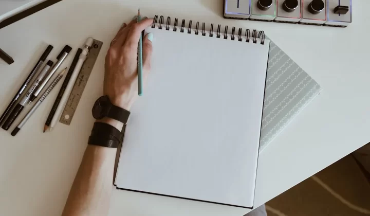 white spiral book with pens and watches