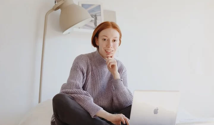 woman in gray sweater sitting on chair using macbook