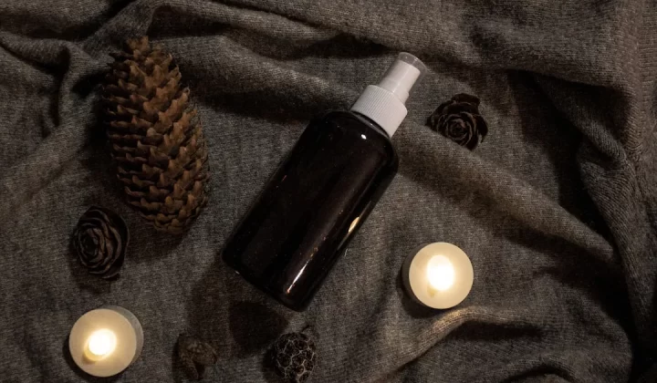 a bottle of lotion sitting on top of a bed next to candles