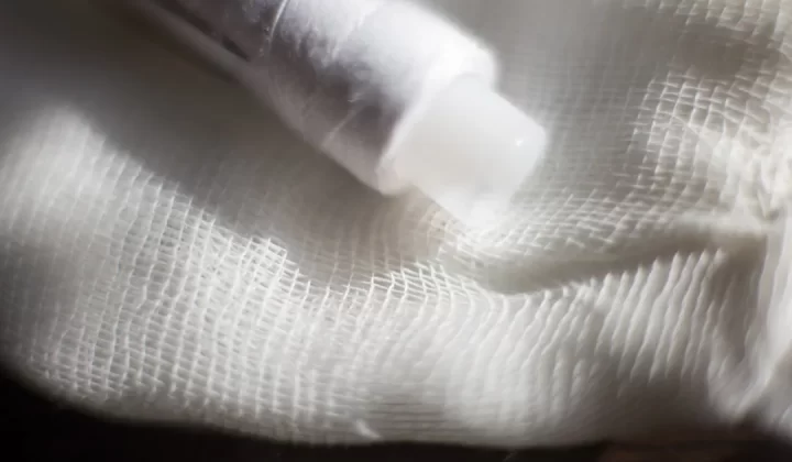 white plastic bottle on white textile