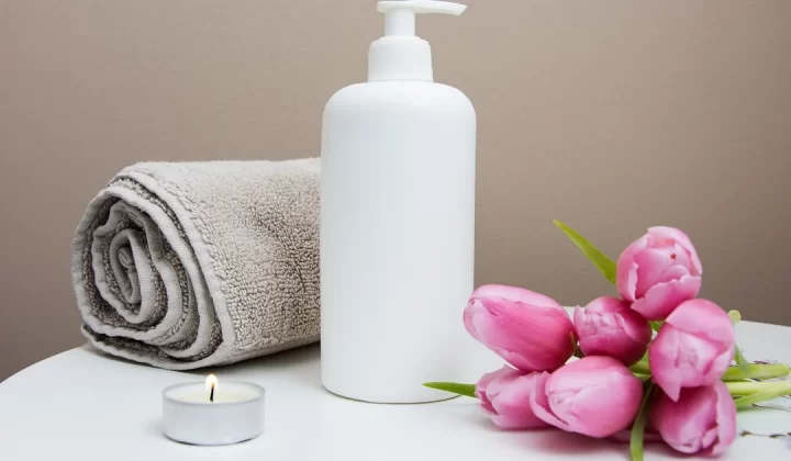 white plastic pump bottle beside pink tulips and gray towel