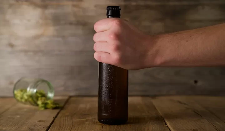 person holding brown glass bottle