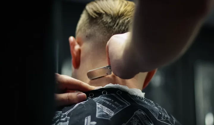 person trimming man's hair
