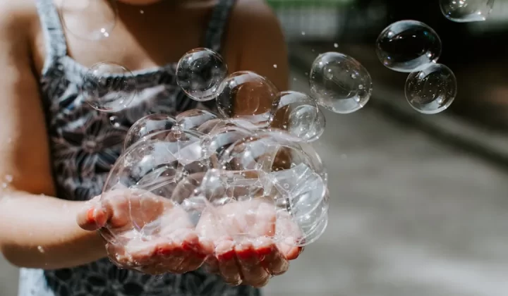 person holding soap bubbles outdoors