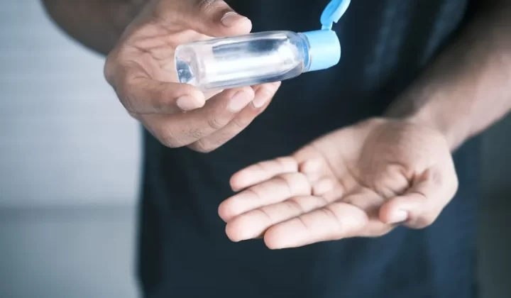person holding clear glass bottle with blue lid