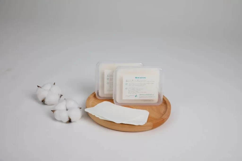 Cotton pads are presented on a wooden tray.
