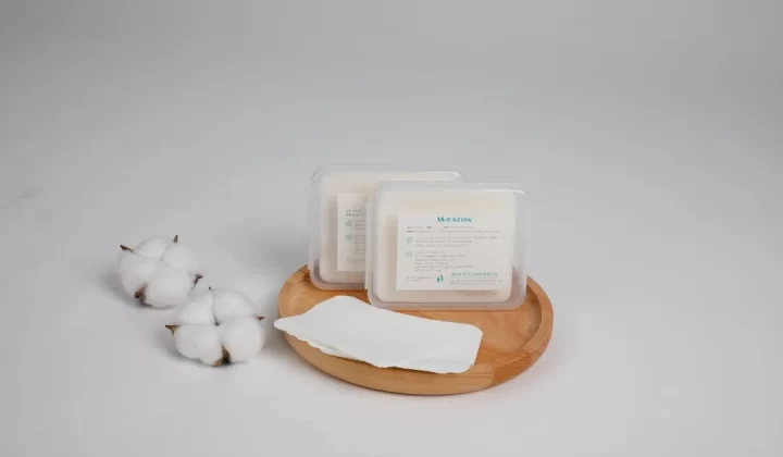 Cotton pads are presented on a wooden tray.